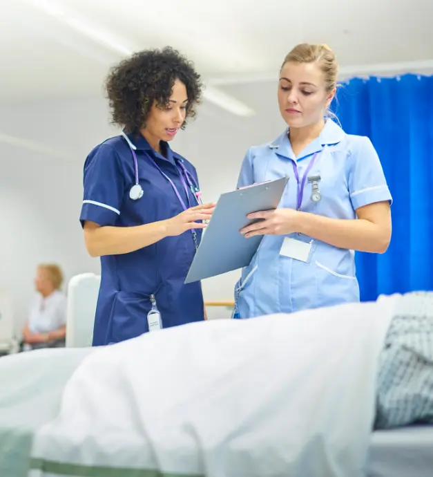 Staffing Solutions Agency 12 Two credentialed registered nurses reviewing medical charts and patient care plans in modern hospital clinical facility